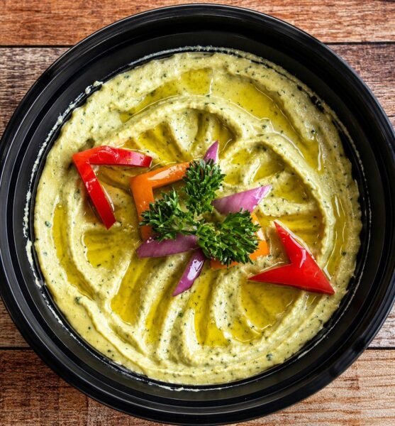 Avocado hummus topped with peppers, red onion and olive oil