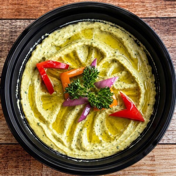Avocado hummus topped with peppers, red onion and olive oil